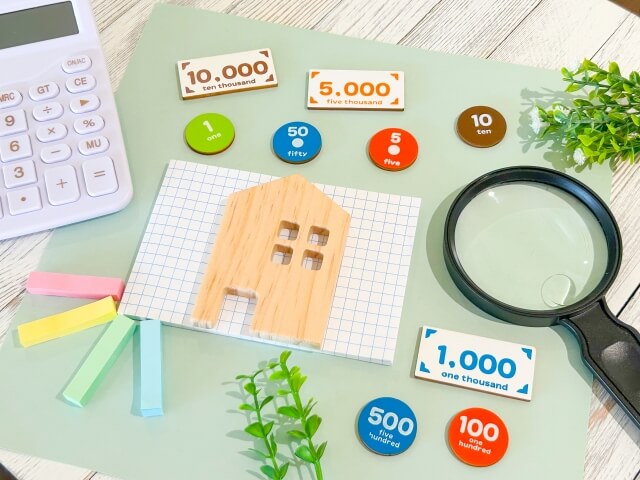 拡大鏡と小さな家の模型と電卓